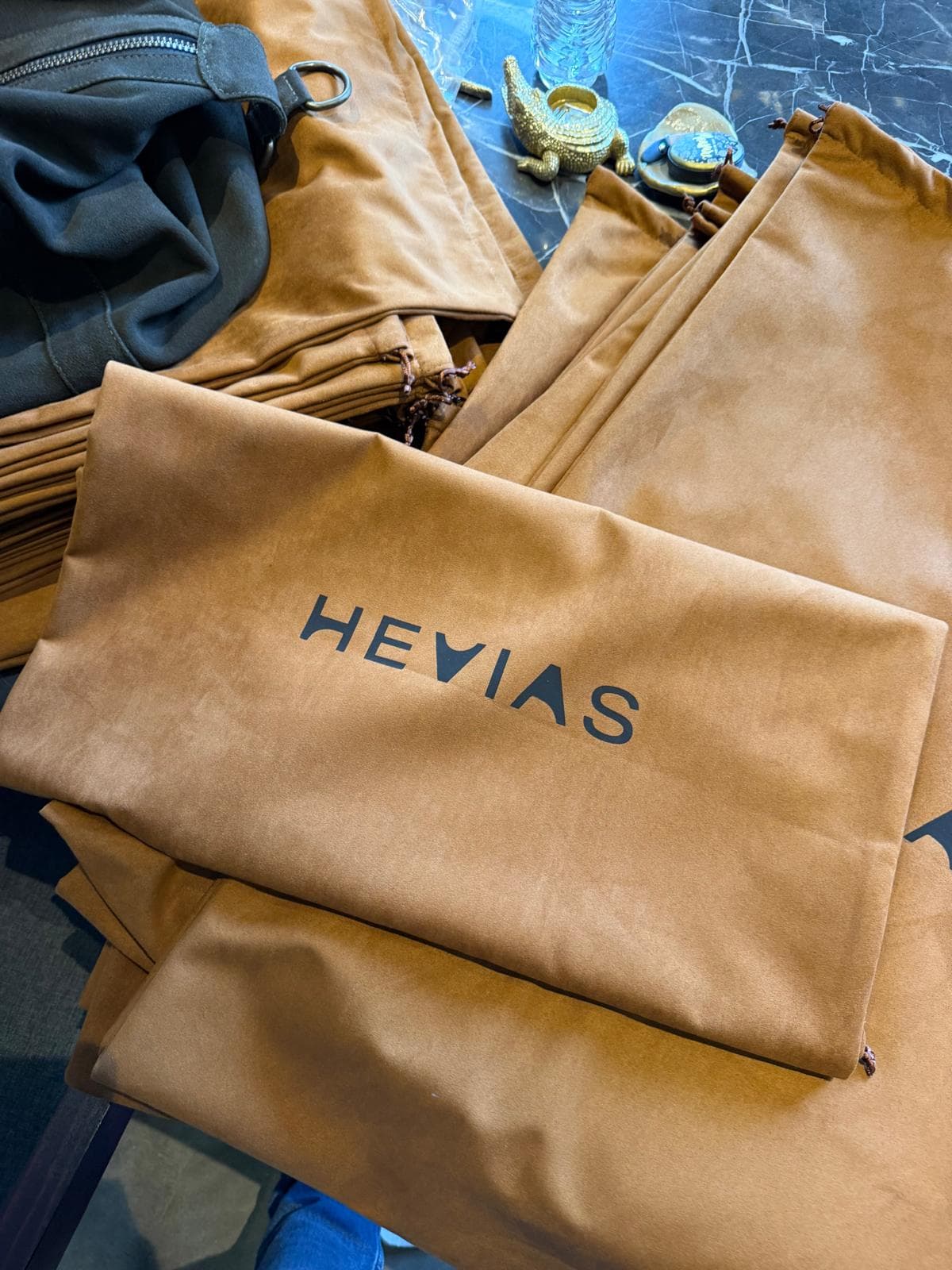 Stack of Hevias camel suede dust bags with screen printed logo